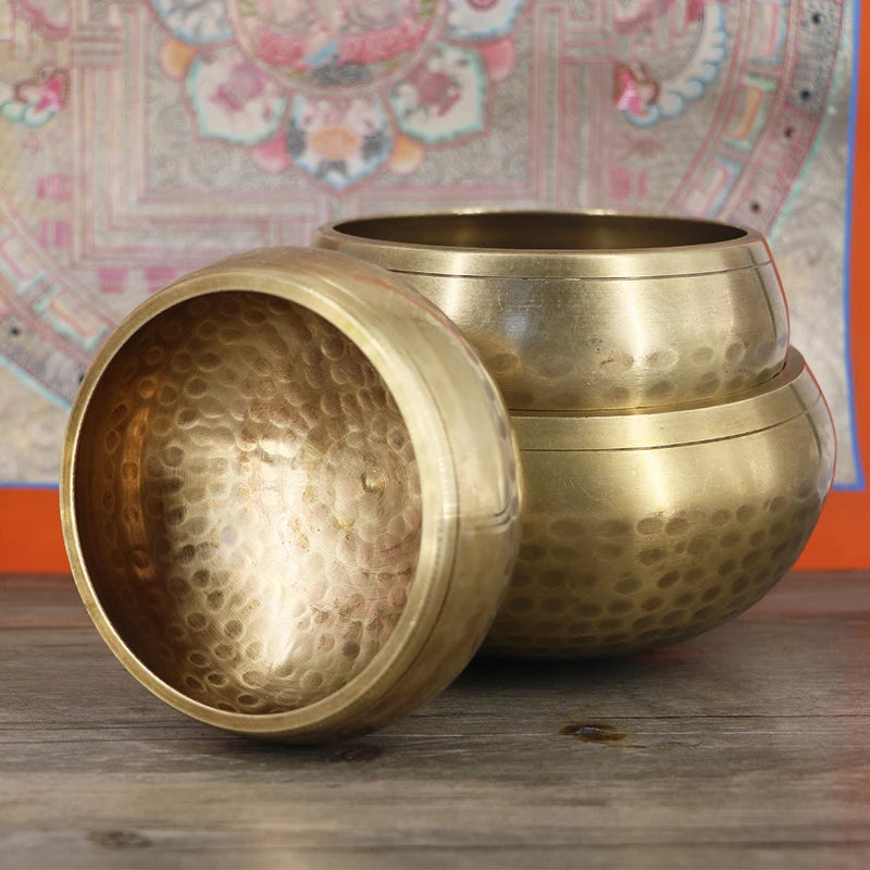 three brass bowls sitting on top of a wooden table