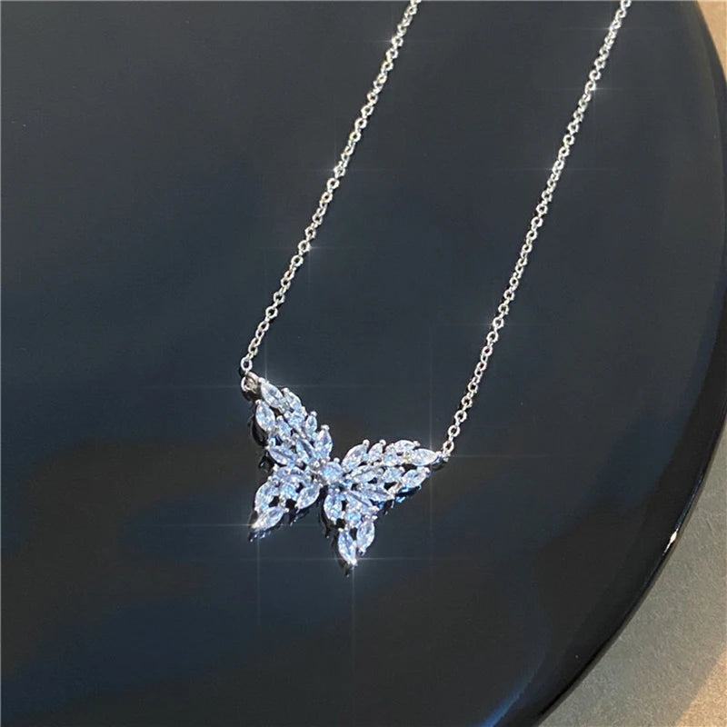a diamond butterfly necklace on a black surface