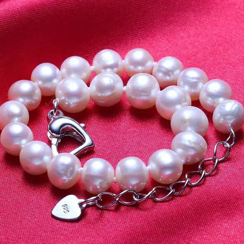 a white pearl bracelet with a heart charm