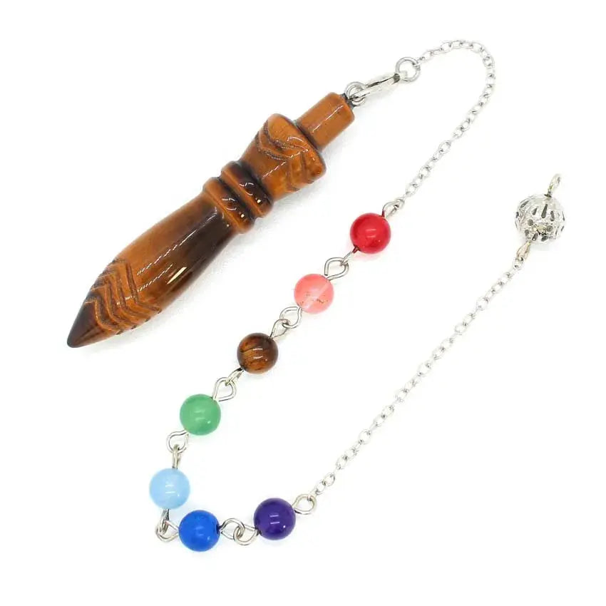 Healing Crystal Pendulum with 7 Chakra Stones - Eye-catching image of the pendant lying on natural stones, signifying healing energy.